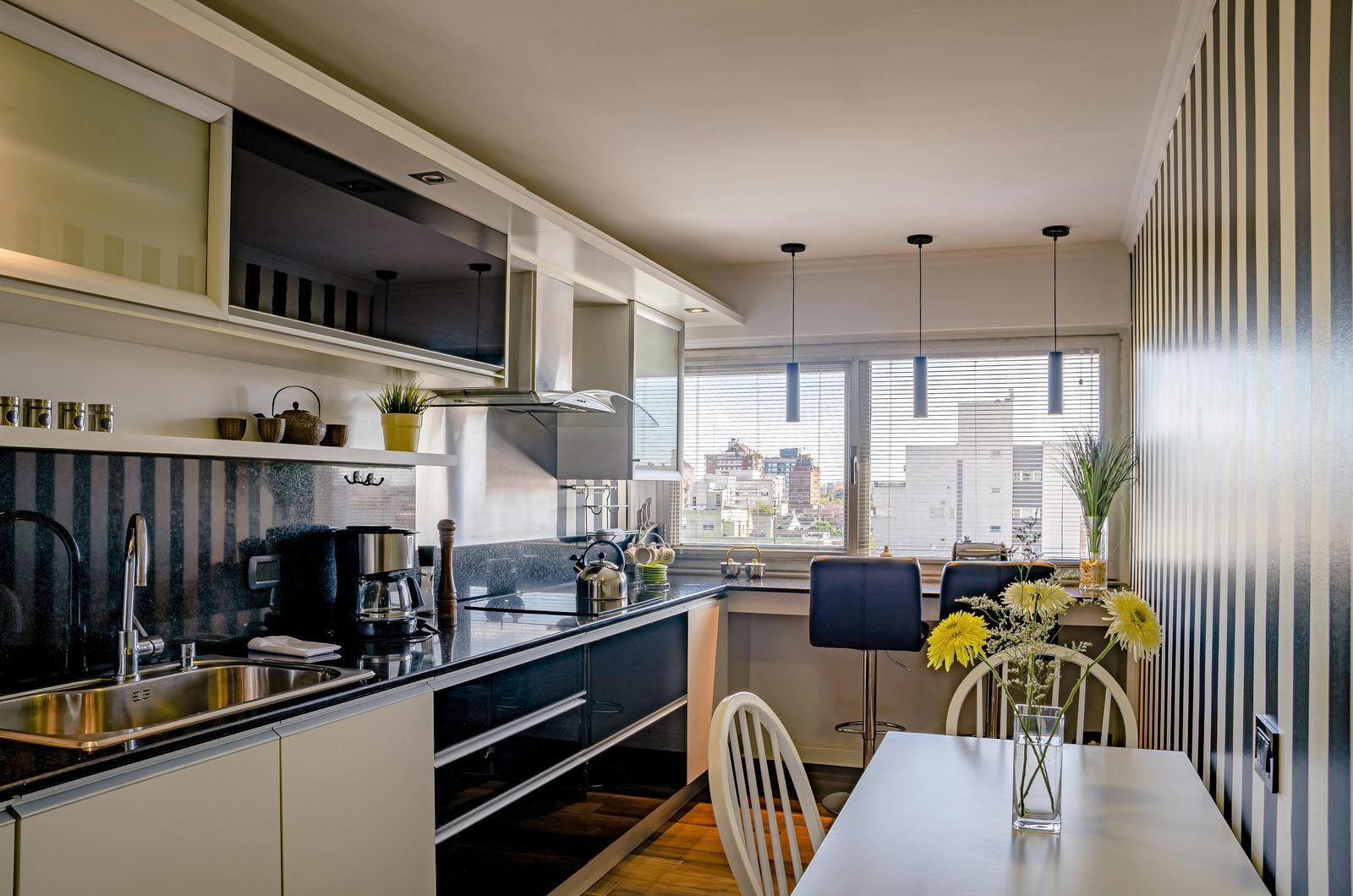 Cozinha gourmet com bancada em granito preto, coifa e vista para a cidade