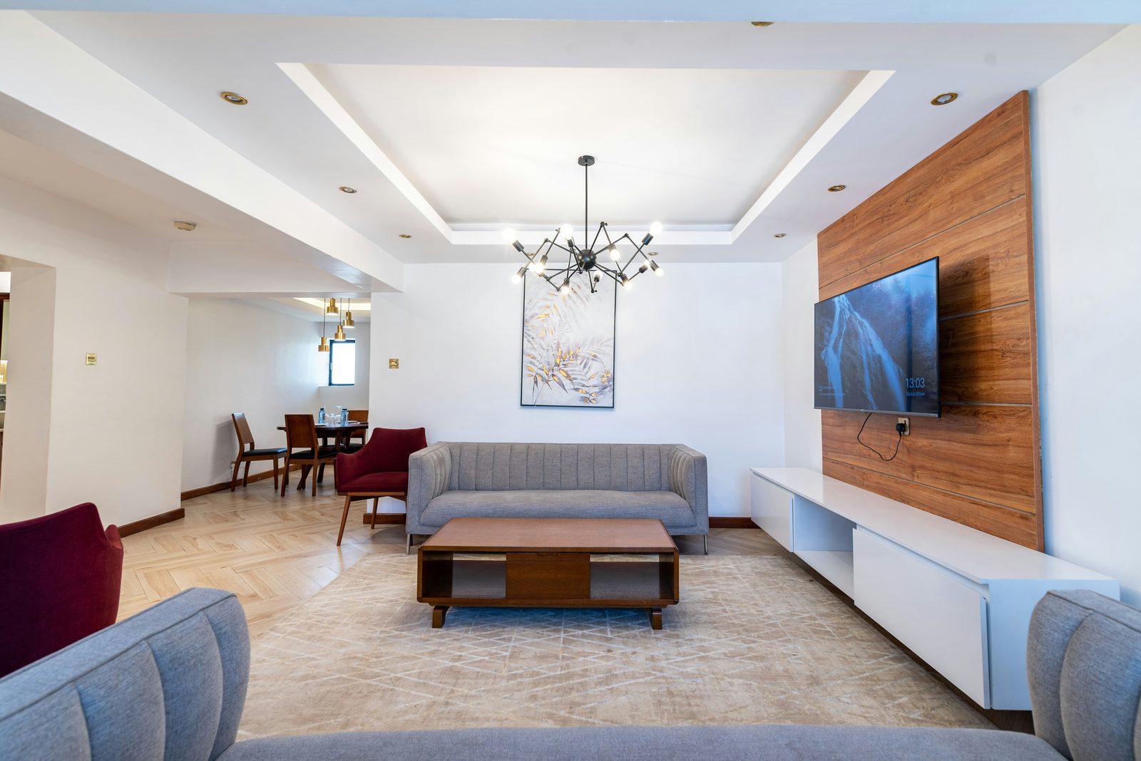 Sala de estar reformada com painel de madeira e sanca iluminada